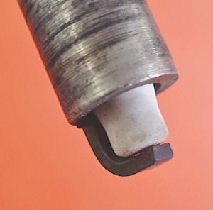 The porcelain insulator tip on this spark plug has broken loose at its base due to a hard impact. The symptoms of a loose insulator tip can include intermittent, rough-running performance complaints.